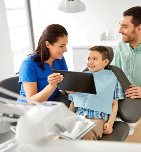 Female dentist showing tablet to child in dental chair